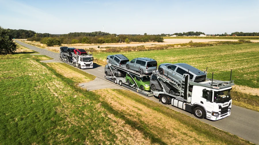Dwa załadowane autotransportery Guess Polska na drodze między polami, widziane z góry.